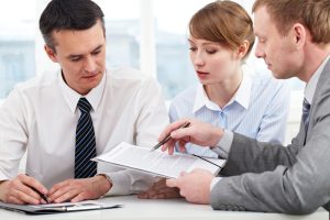 Photo of confident employees discussing papers at meeting