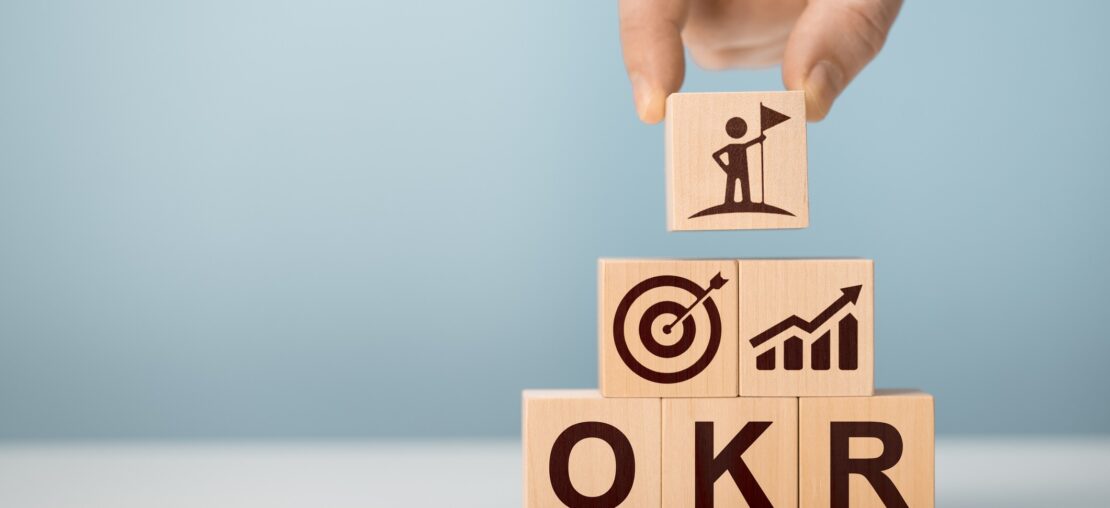 Equipe de gestão analisando painel de OKRs e fluxo de processos em escritório moderno